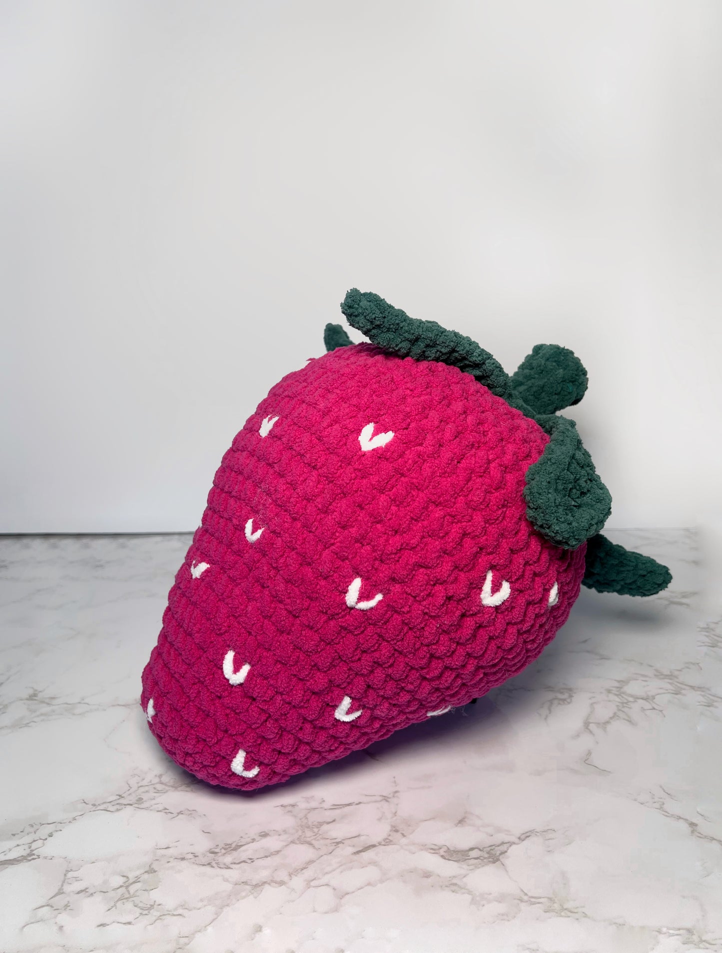 crochet pink strawberry, with white seeds and green stem. 